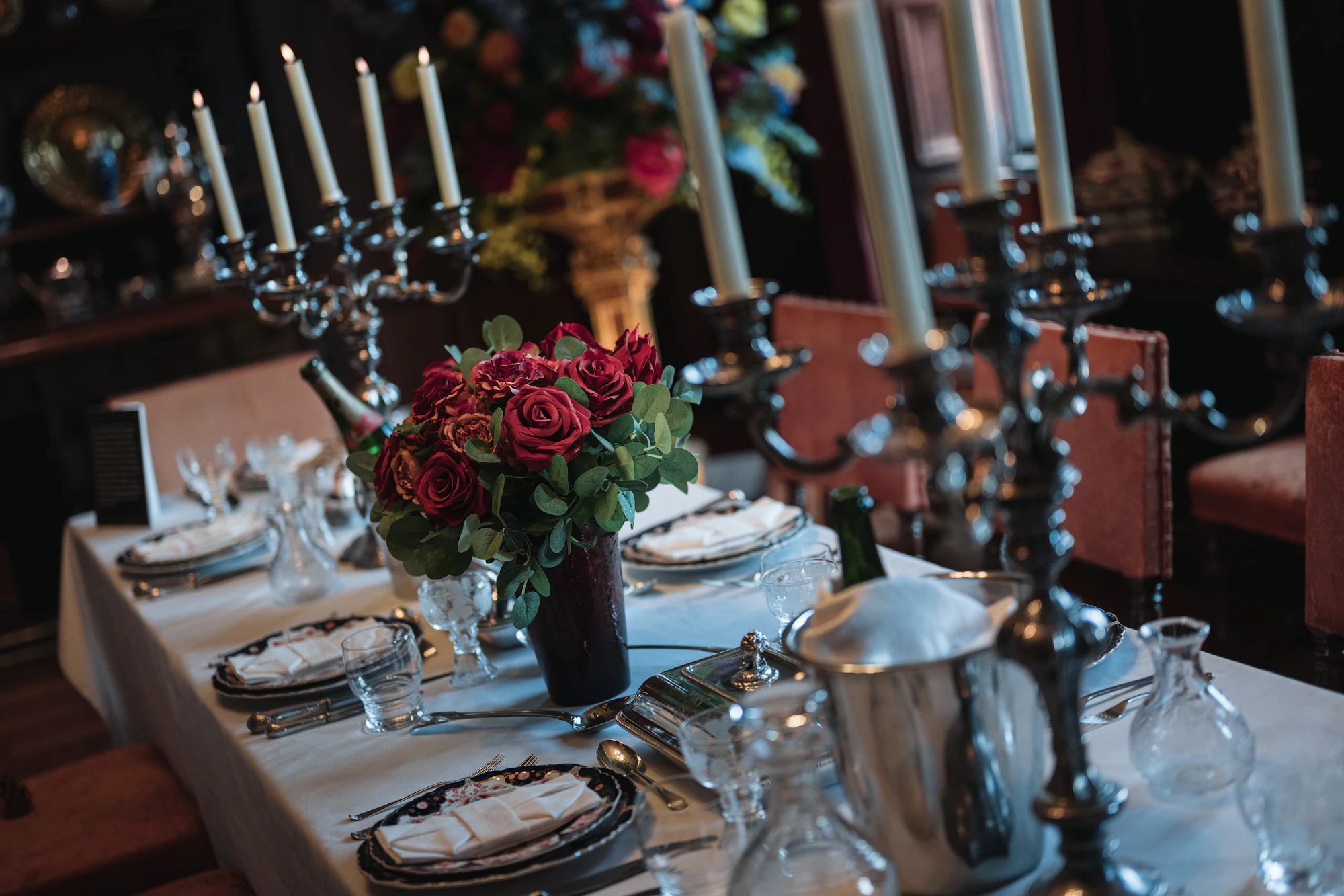 A formal dining table set with candelabras and red roses