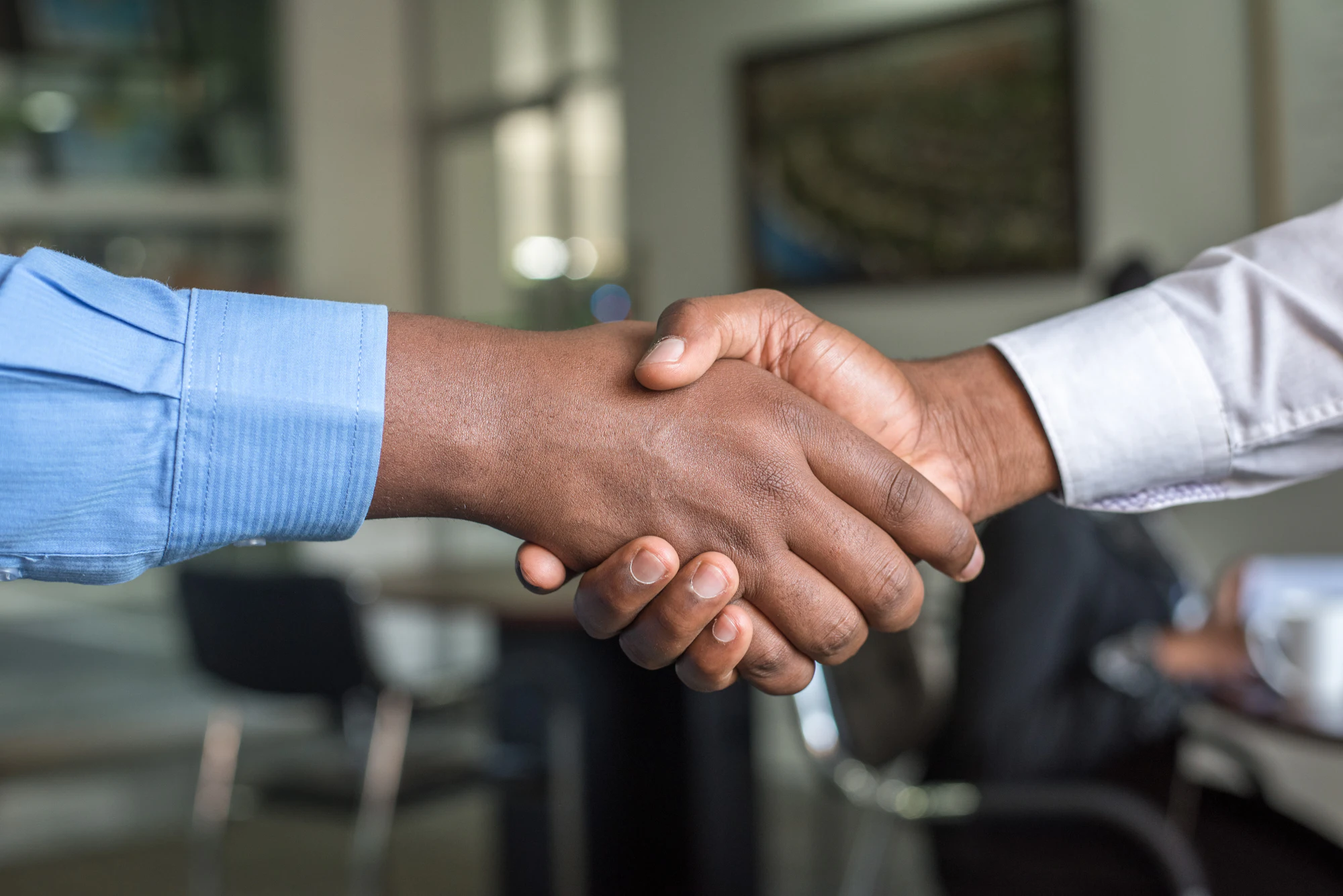 Two business partners shaking hands across a table